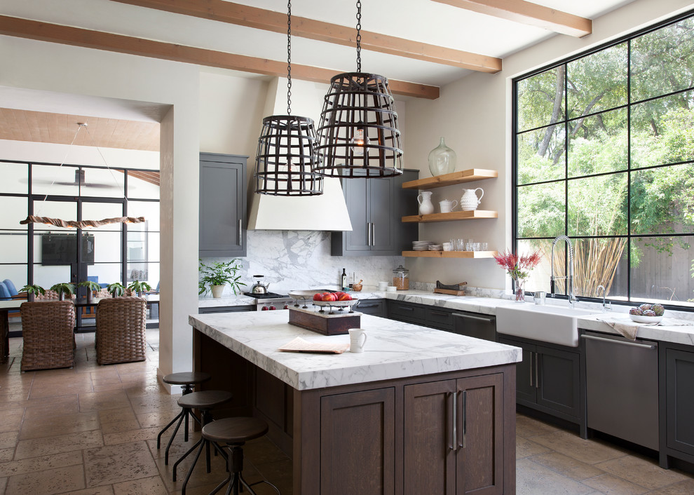 Inspiration for a mediterranean kitchen in Austin with a farmhouse sink, shaker cabinets, grey cabinets, white splashback, stainless steel appliances, with island, stone slab splashback and travertine floors.