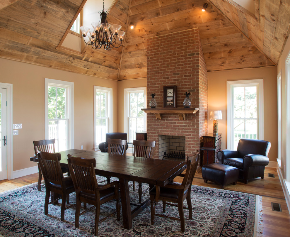 Country dining room in Baltimore with medium hardwood floors, a standard fireplace and a brick fireplace surround.