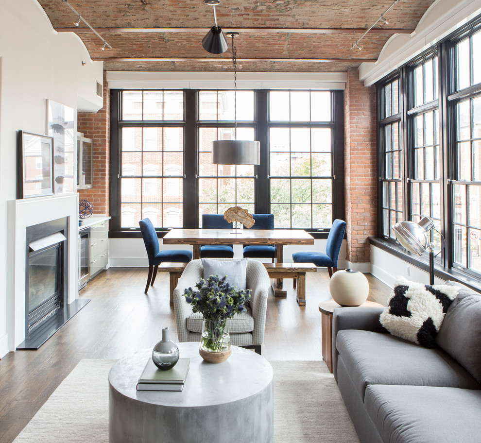 Photo of an industrial open concept living room in New York with white walls, dark hardwood floors and a standard fireplace.