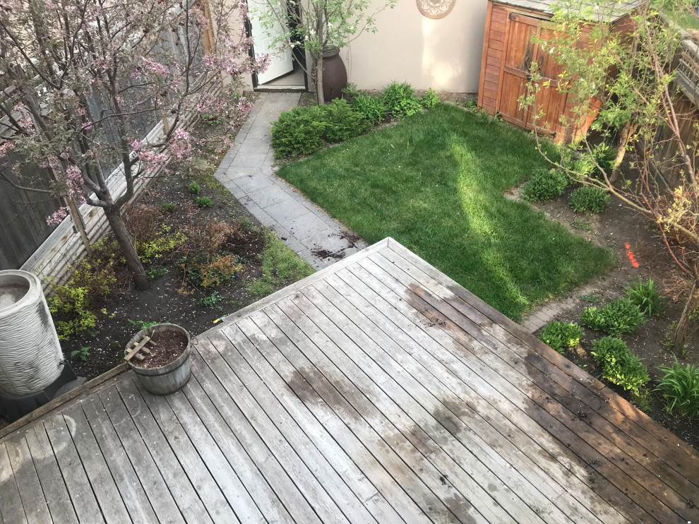 Kleiner Klassischer Garten im Sommer, hinter dem Haus mit Gehweg, direkter Sonneneinstrahlung, Betonboden und Holzzaun in Calgary