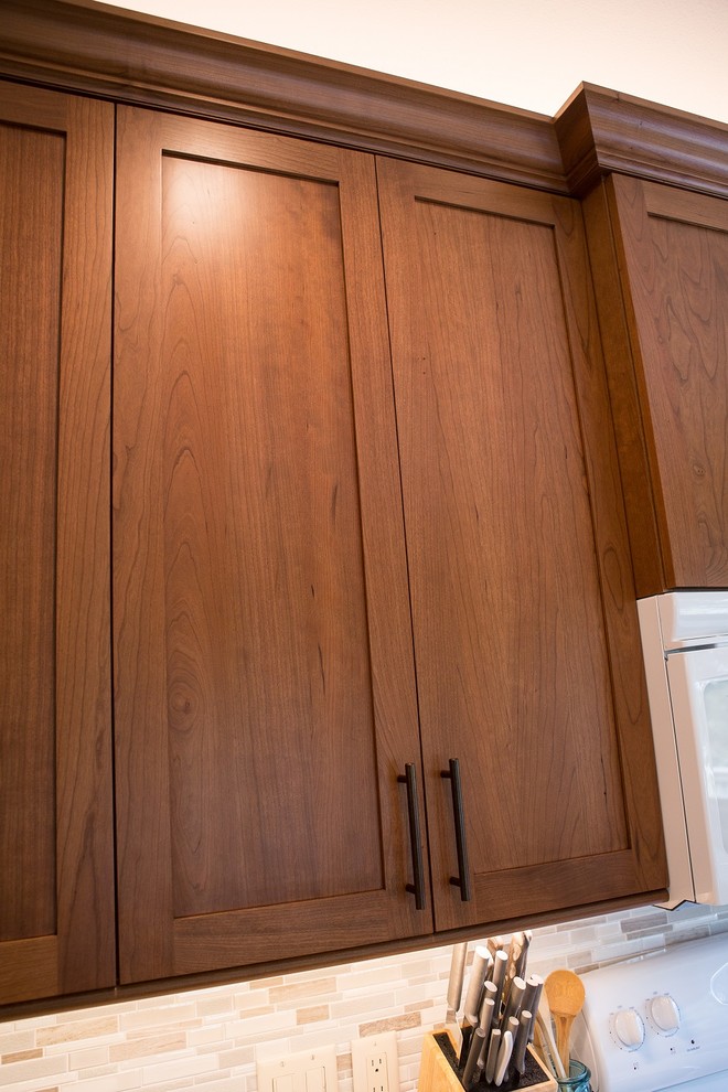 Large transitional l-shaped light wood floor eat-in kitchen photo in Cedar Rapids with a double-bowl sink, recessed-panel cabinets, medium tone wood cabinets, laminate countertops, multicolored backsplash, mosaic tile backsplash, white appliances and an island