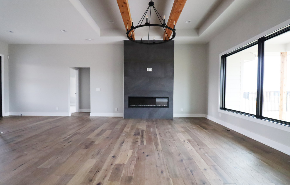 Ejemplo de salón abierto moderno con suelo de madera clara, chimenea lineal, marco de chimenea de baldosas y/o azulejos, televisor colgado en la pared y vigas vistas