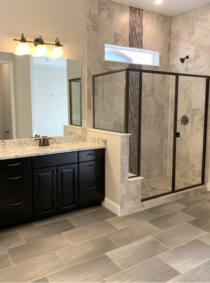 Photo of a transitional bathroom in Denver with raised-panel cabinets, dark wood cabinets, gray tile, porcelain tile, grey walls, porcelain floors, granite benchtops and grey floor.