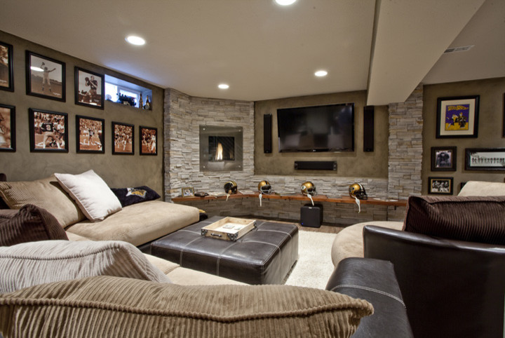 This is an example of a large transitional fully buried basement in Indianapolis with medium hardwood floors, a standard fireplace, a metal fireplace surround, brown walls and brown floor.