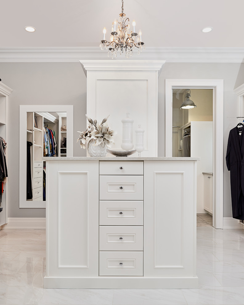 Large transitional gender-neutral walk-in wardrobe in Edmonton with white cabinets, porcelain floors, beige floor and recessed-panel cabinets.