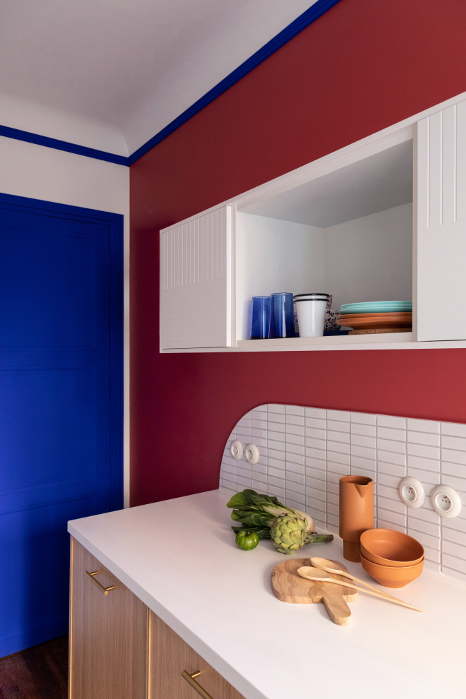 Cette photo montre une petite cuisine américaine linéaire moderne en bois clair avec un évier 1 bac, un placard à porte affleurante, un plan de travail en stratifié, une crédence blanche, une crédence en mosaïque, un électroménager blanc, carreaux de ciment au sol, un sol rouge et un plan de travail blanc.