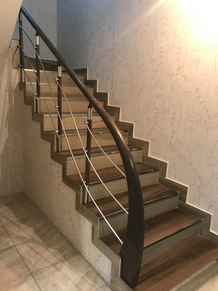 На фото: изогнутая лестница среднего размера в современном стиле с акриловыми ступенями, подступенками из мрамора, деревянными перилами и обоями на стенах с