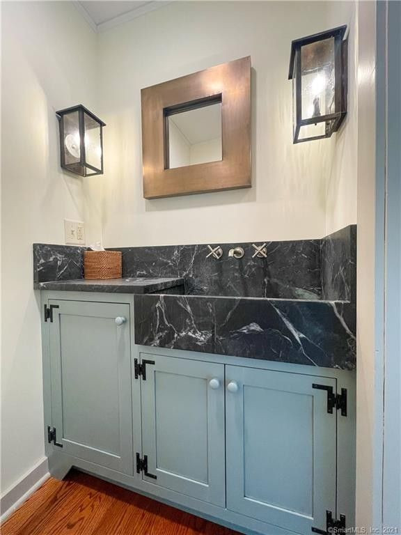 This is an example of a traditional powder room in Bridgeport with shaker cabinets, blue cabinets, medium hardwood floors, a trough sink, soapstone benchtops, black benchtops and a built-in vanity.