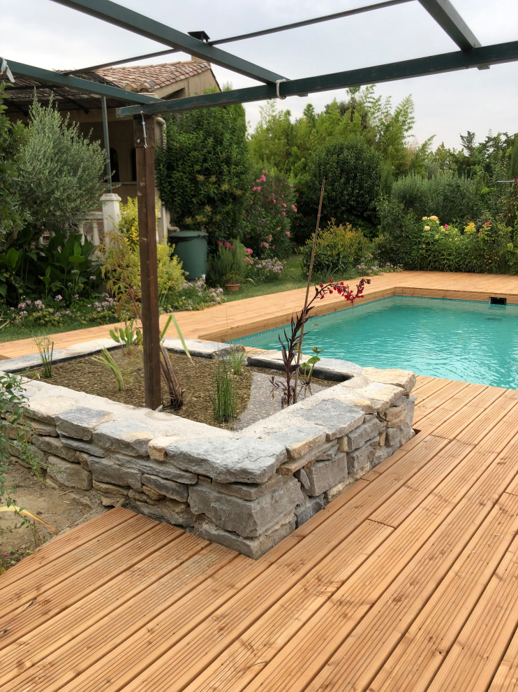 Diseño de piscina natural de estilo de casa de campo de tamaño medio rectangular en patio lateral con entablado