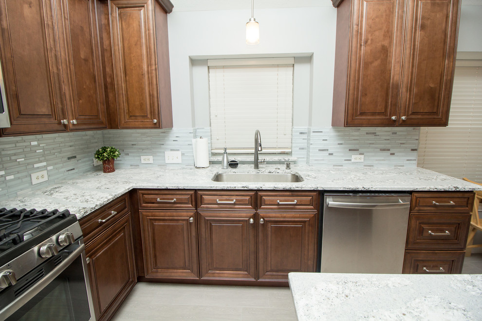 Open concept kitchen - mid-sized transitional l-shaped porcelain tile and gray floor open concept kitchen idea in Houston with a single-bowl sink, raised-panel cabinets, medium tone wood cabinets, quartz countertops, mosaic tile backsplash, stainless steel appliances, two islands and white backsplash