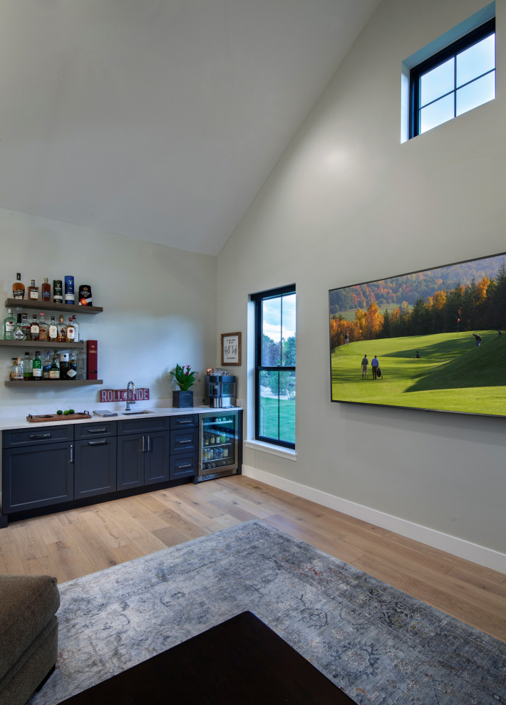 Foto di un grande soggiorno country chiuso con angolo bar, pareti grigie, parquet chiaro, TV a parete, pavimento marrone e soffitto a volta