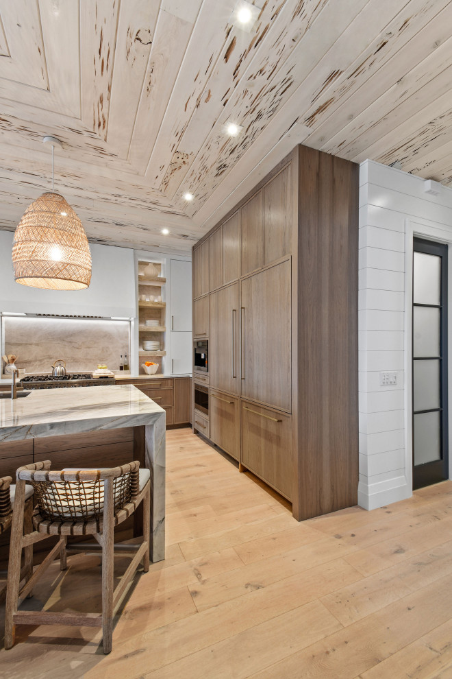 Photo of a mid-sized beach style l-shaped open plan kitchen in Other with distressed cabinets, quartzite benchtops, panelled appliances and with island.