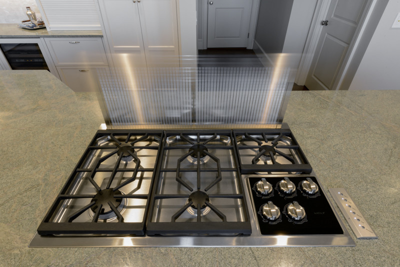 Transitional medium tone wood floor kitchen photo in Boston with a triple-bowl sink, recessed-panel cabinets, white cabinets, granite countertops, white backsplash, mosaic tile backsplash, stainless steel appliances and an island