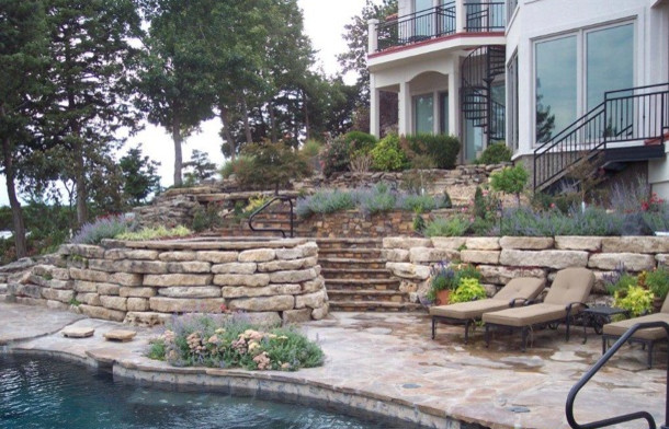 Photo of a transitional backyard stone retaining wall landscape.