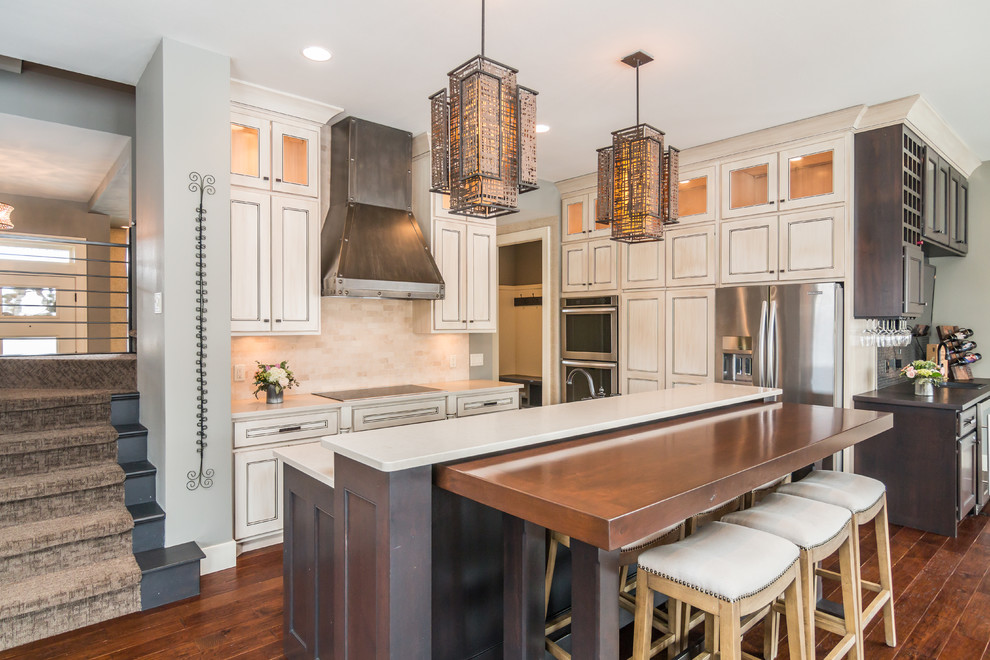 Kitchen - transitional medium tone wood floor and orange floor kitchen idea with recessed-panel cabinets, beige cabinets, beige backsplash, stainless steel appliances and two islands
