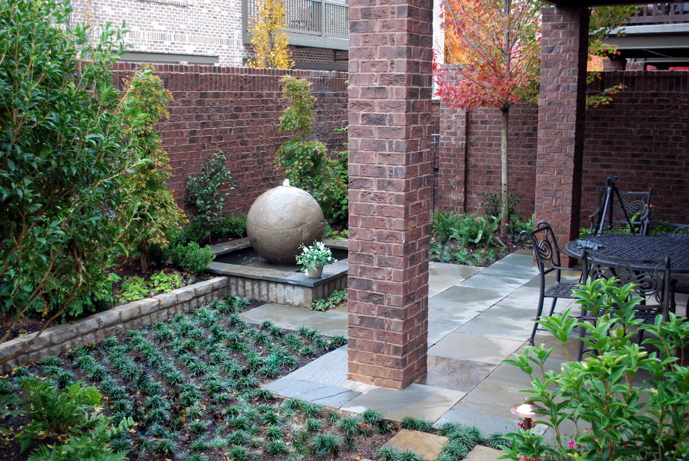 This is an example of a traditional courtyard patio in Atlanta with a water feature.