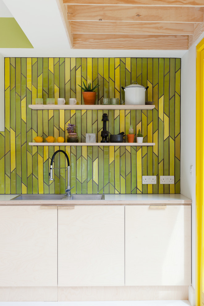 Contemporary kitchen in London with flat-panel cabinets and yellow splashback.