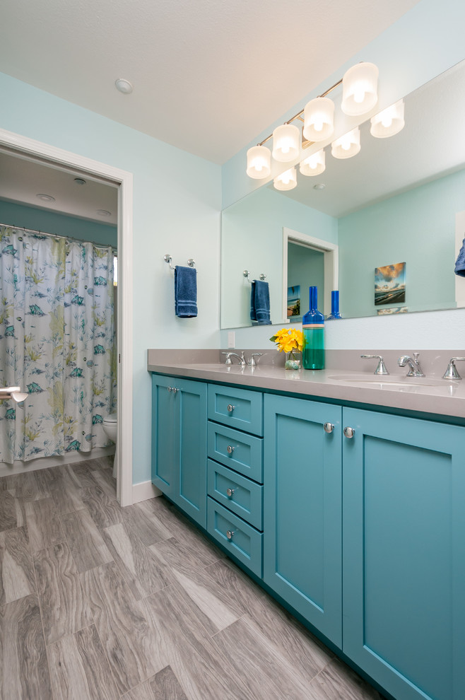 This is an example of a mid-sized transitional kids bathroom in San Francisco with a wall-mount sink, shaker cabinets, blue cabinets, engineered quartz benchtops, an alcove tub, a shower/bathtub combo, gray tile, porcelain tile, blue walls and porcelain floors.