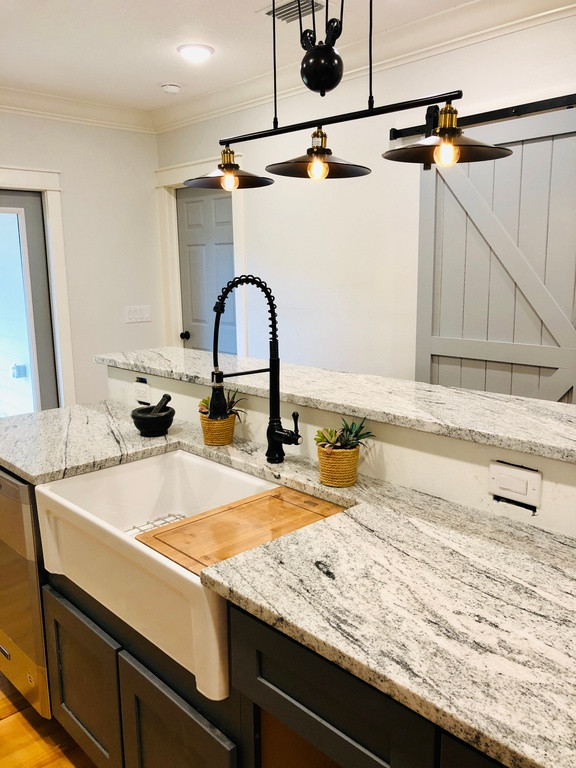 Mid-sized midcentury galley kitchen pantry in Tampa with a farmhouse sink, shaker cabinets, white cabinets, granite benchtops, grey splashback, ceramic splashback, stainless steel appliances, medium hardwood floors, with island, brown floor and grey benchtop.