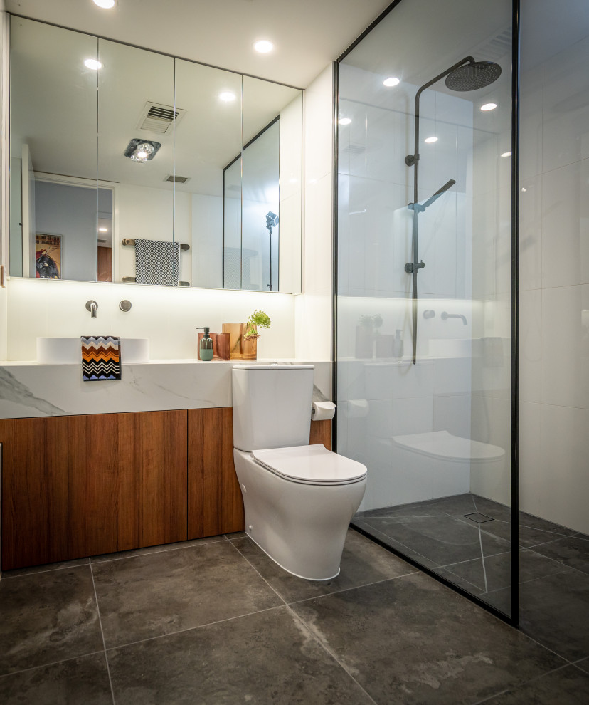 Mid-sized contemporary master bathroom in Melbourne with white tile, white walls, a vessel sink, engineered quartz benchtops, grey floor, a single vanity, a built-in vanity, flat-panel cabinets, medium wood cabinets, a curbless shower, a two-piece toilet, an open shower and white benchtops.