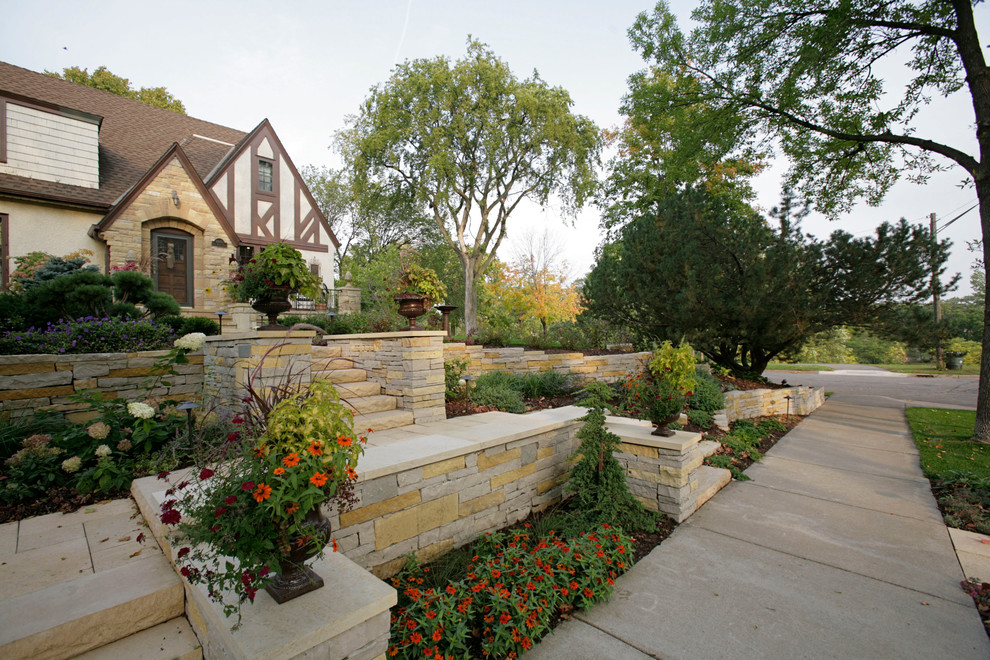 Photo of a mid-sized country front yard garden in Minneapolis with a retaining wall and concrete pavers.