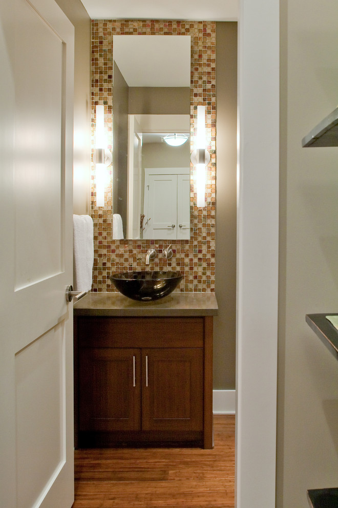 This is an example of a mid-sized contemporary powder room in Vancouver with a vessel sink, shaker cabinets, dark wood cabinets, brown tile, mosaic tile, brown walls, medium hardwood floors, brown floor and grey benchtops.