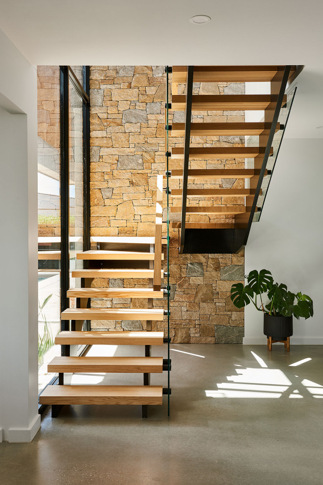 На фото: большая п-образная лестница в морском стиле с деревянными ступенями и стеклянными перилами с