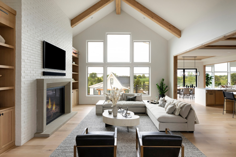 Design ideas for a transitional open concept living room in Minneapolis with white walls, light hardwood floors, a standard fireplace, a stone fireplace surround, a wall-mounted tv, vaulted and brown floor.
