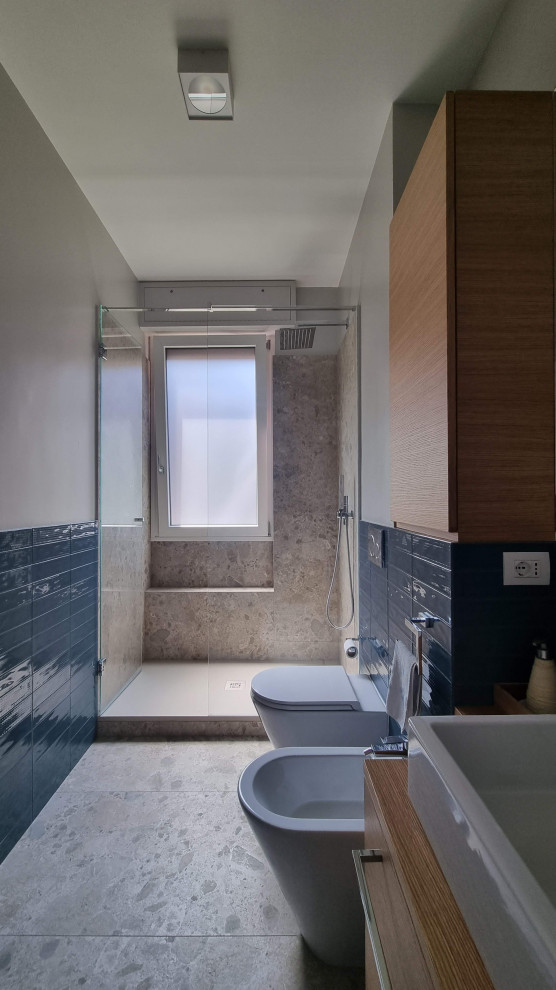 Inredning av ett modernt stort badrum med dusch, med släta luckor, en dusch i en alkov, en toalettstol med separat cisternkåpa, blå kakel, porslinskakel, beige väggar, klinkergolv i porslin, ett fristående handfat, träbänkskiva och dusch med gångjärnsdörr