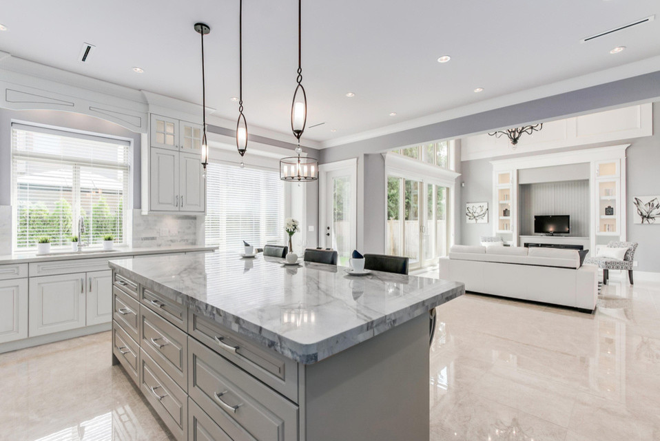 Open concept kitchen - large transitional u-shaped porcelain tile open concept kitchen idea in Vancouver with an undermount sink, raised-panel cabinets, white cabinets, marble countertops, gray backsplash, stone tile backsplash, stainless steel appliances and an island