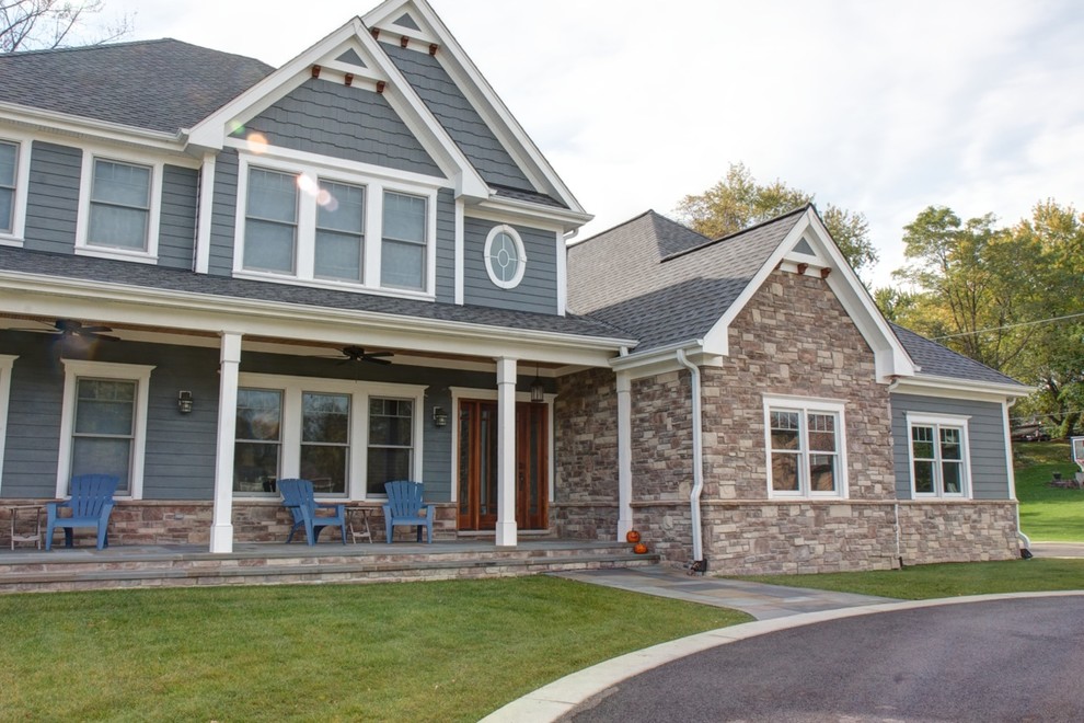 Large traditional two-storey blue exterior in Chicago with stone veneer and a gambrel roof.
