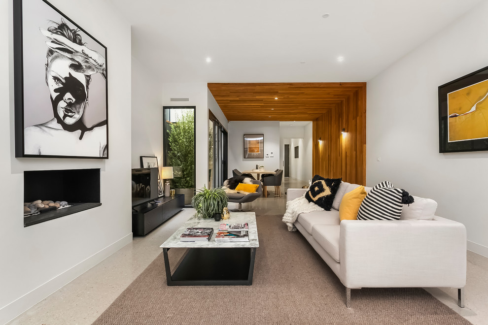 Contemporary living room in Melbourne with white walls, a ribbon fireplace and grey floor.