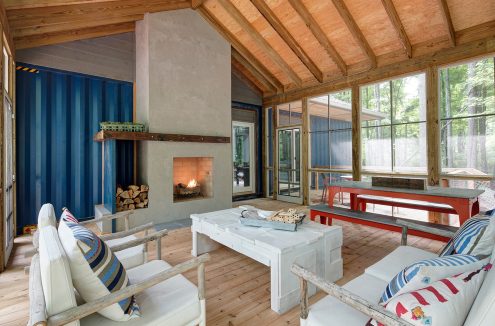 Inspiration for a country sunroom in Other with light hardwood floors, a standard fireplace, a concrete fireplace surround and a standard ceiling.