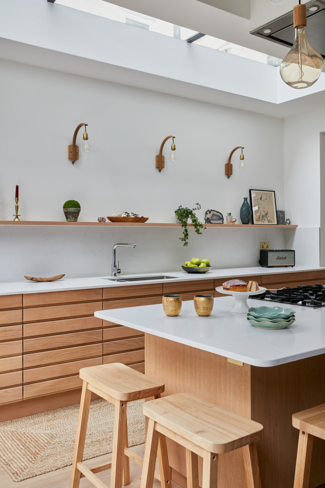 This is an example of a medium sized scandinavian open plan kitchen in London with composite countertops and an island.