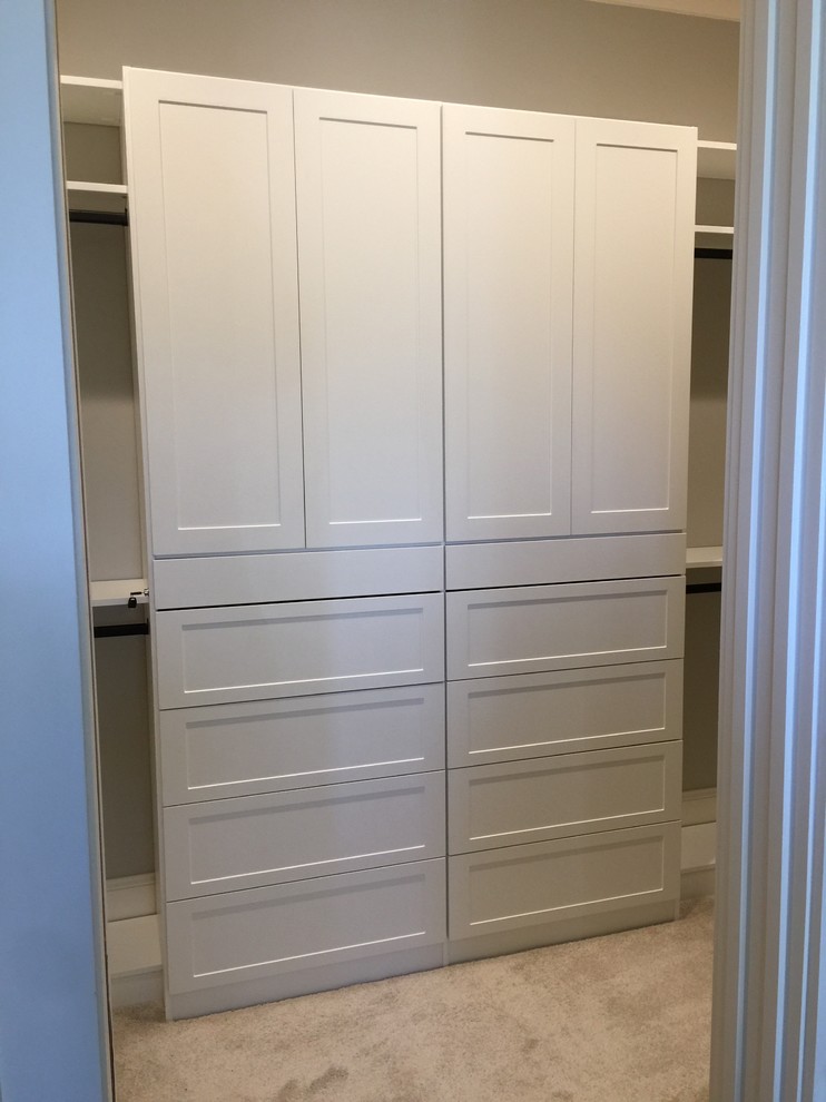 This is an example of a mid-sized transitional gender-neutral walk-in wardrobe in Other with shaker cabinets, white cabinets, carpet and grey floor.
