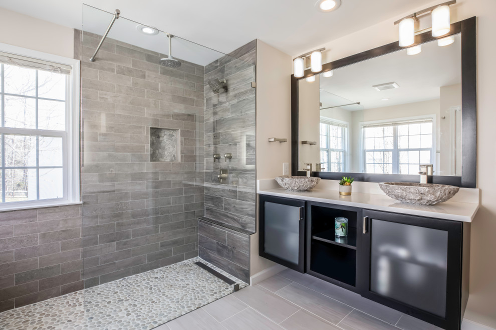 Design ideas for a mid-sized transitional master bathroom in DC Metro with black cabinets, a freestanding tub, a two-piece toilet, gray tile, grey walls, ceramic floors, a vessel sink, granite benchtops, grey floor, a hinged shower door and white benchtops.