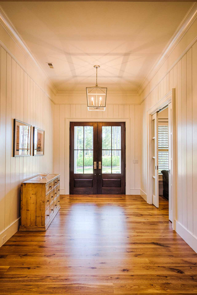 Example of a light wood floor, brown floor and shiplap wall front door design with a dark wood front door