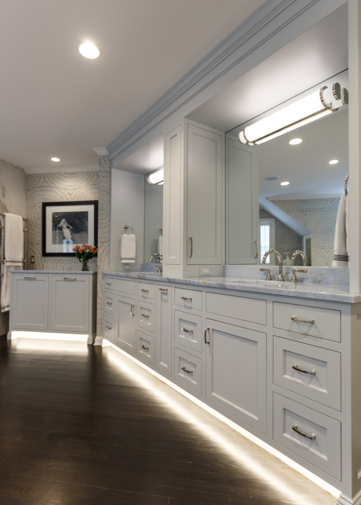 This is an example of an expansive transitional master bathroom in New York with recessed-panel cabinets, grey cabinets, a freestanding tub, a double shower, multi-coloured walls, dark hardwood floors, an undermount sink, marble benchtops, a hinged shower door, blue benchtops, an enclosed toilet, a double vanity, a built-in vanity and wallpaper.