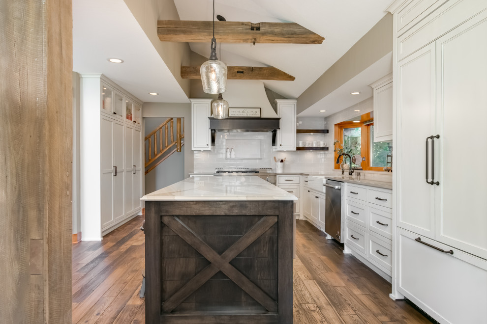 Inspiration for a large beach style l-shaped open plan kitchen in Minneapolis with a farmhouse sink, flat-panel cabinets, white cabinets, quartz benchtops, white splashback, ceramic splashback, stainless steel appliances, dark hardwood floors, with island, brown floor and beige benchtop.