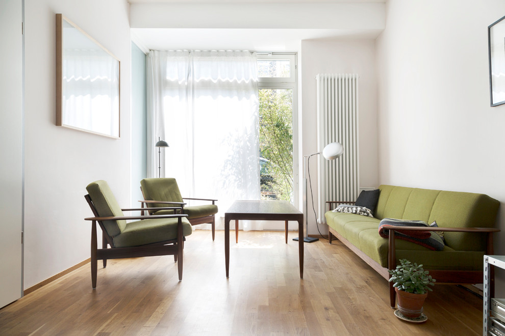 Mid-sized midcentury enclosed living room in Berlin with white walls, medium hardwood floors and no fireplace.