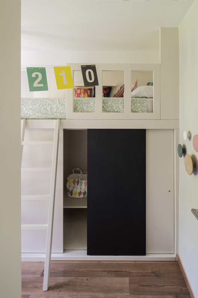 Mid-sized contemporary gender-neutral kids' bedroom in Barcelona with white walls, medium hardwood floors and brown floor for kids 4-10 years old.