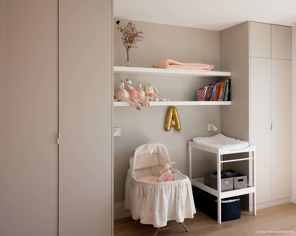 Aménagement d'une chambre de bébé fille contemporaine de taille moyenne avec un mur beige, parquet clair et un sol marron.