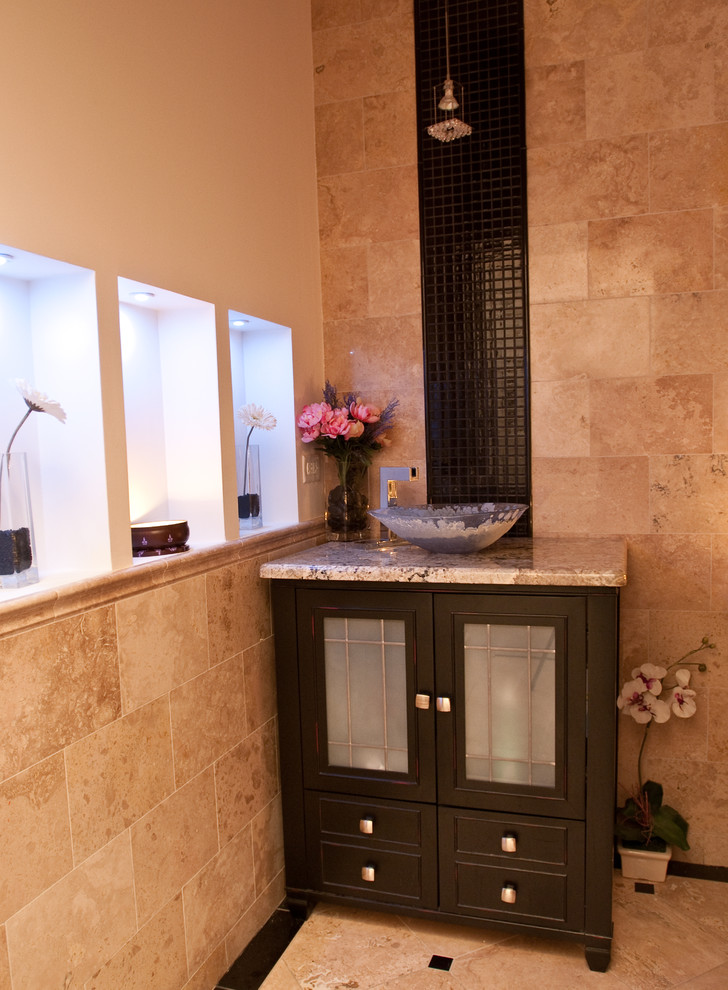 This is an example of a mid-sized mediterranean 3/4 bathroom in New York with glass-front cabinets, dark wood cabinets, a two-piece toilet, beige tile, black tile, mosaic tile, beige walls, ceramic floors, a vessel sink, granite benchtops and beige floor.