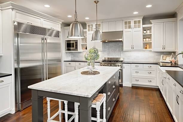 Inspiration for a mid-sized transitional u-shaped eat-in kitchen in Philadelphia with a farmhouse sink, recessed-panel cabinets, white cabinets, soapstone benchtops, white splashback, stainless steel appliances, dark hardwood floors, with island, brown floor and black benchtop.