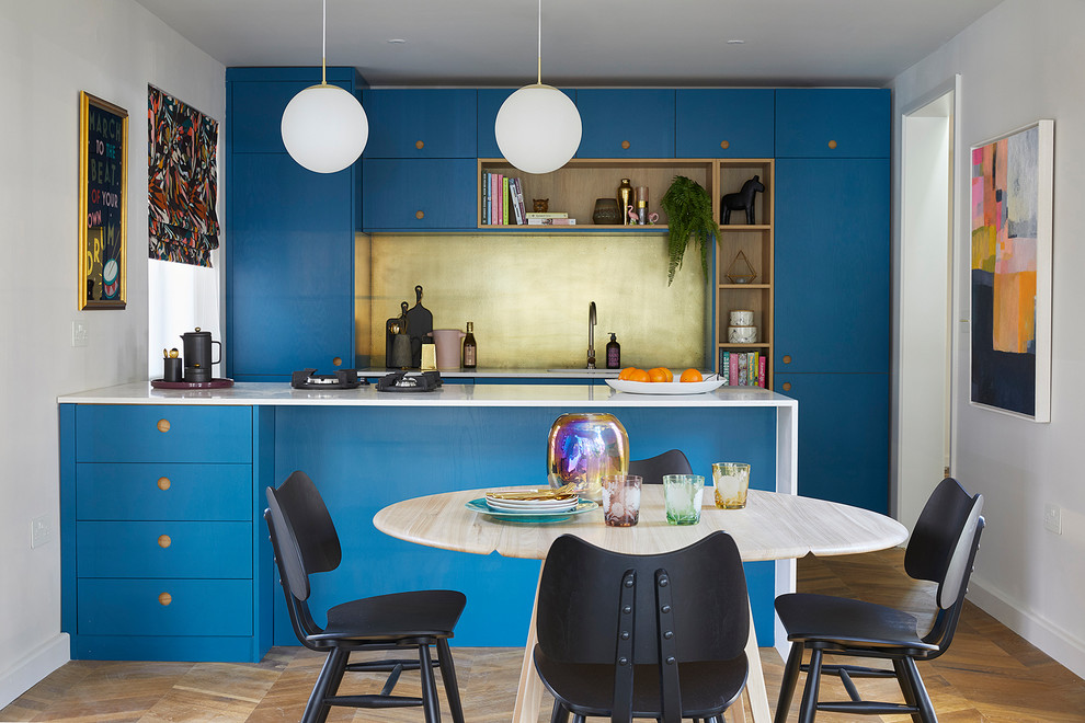 Photo of a contemporary galley kitchen in Melbourne with flat-panel cabinets, blue cabinets, metallic splashback, panelled appliances, medium hardwood floors, a peninsula, brown floor and white benchtop.