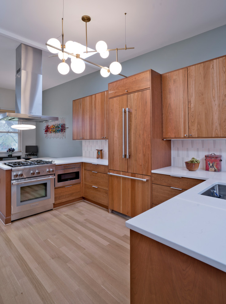 ワシントンD.C.にあるラグジュアリーな中くらいなミッドセンチュリースタイルのおしゃれなキッチン (アンダーカウンターシンク、フラットパネル扉のキャビネット、中間色木目調キャビネット、クオーツストーンカウンター、白いキッチンパネル、セラミックタイルのキッチンパネル、パネルと同色の調理設備、淡色無垢フローリング、ベージュの床、白いキッチンカウンター、三角天井) の写真