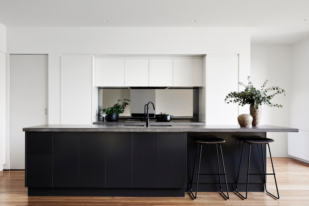 Ispirazione per una cucina minimal di medie dimensioni con ante bianche, top in cemento, paraspruzzi a specchio e parquet chiaro