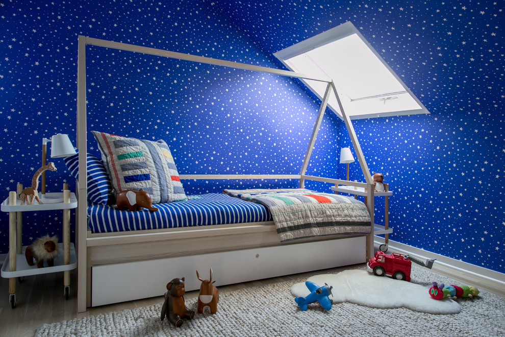 This is an example of a mid-sized eclectic kids' bedroom for kids 4-10 years old and boys in New York with blue walls, light hardwood floors and beige floor.