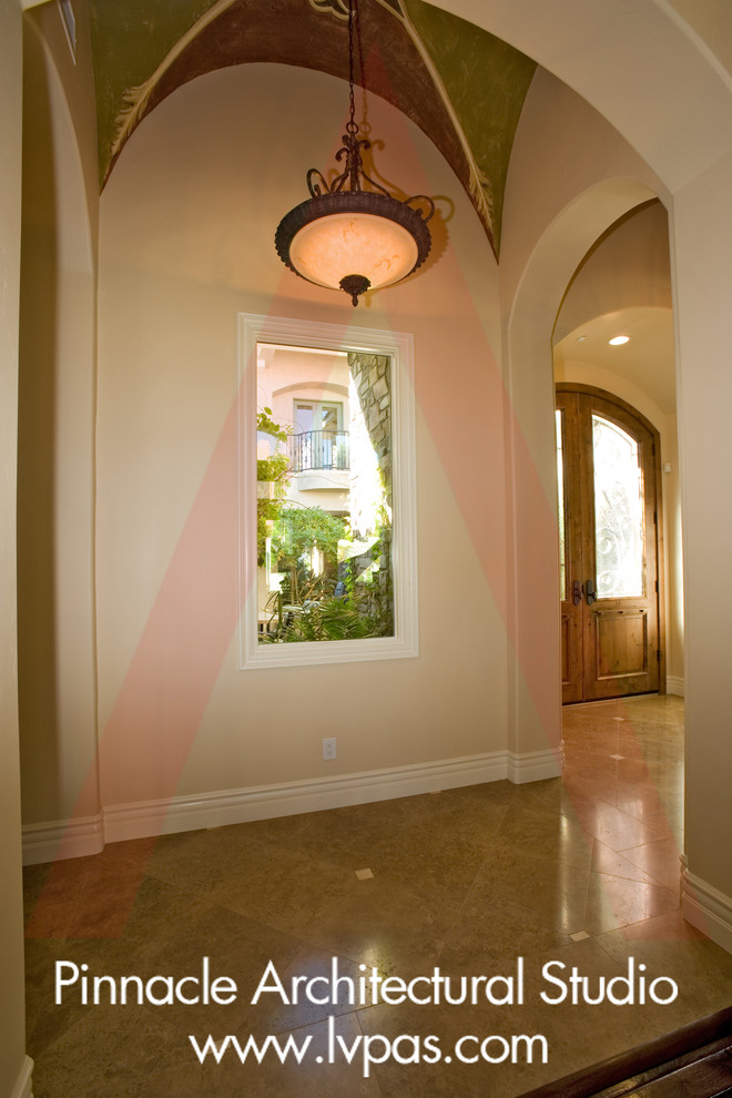 This is an example of an expansive mediterranean hallway in Las Vegas with beige walls and brown floor.