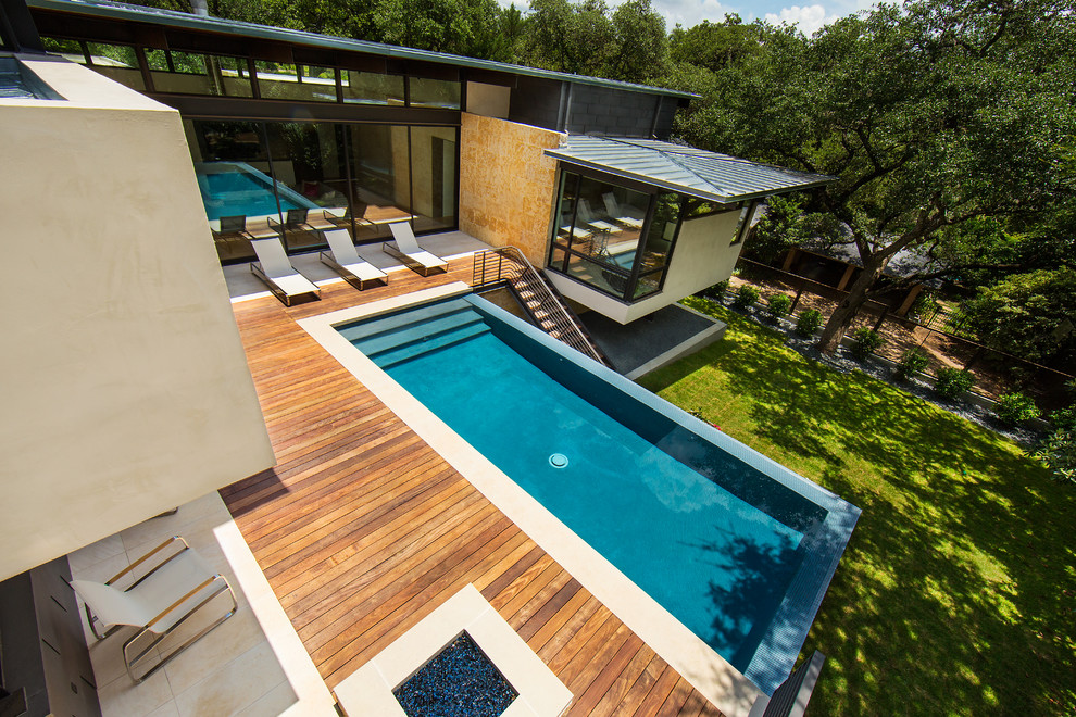 Design ideas for a mid-sized modern backyard rectangular infinity pool in Austin with decking.